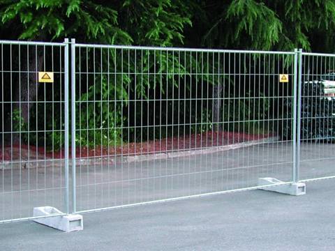 A cerca portátil de Austrália é instalada na rua atrás de um parque.