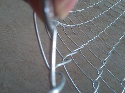 O PVC revestiu a cerca do elo de corrente com os furos da forma do diamante e as extremidades da torção são colocadas no assoalho.